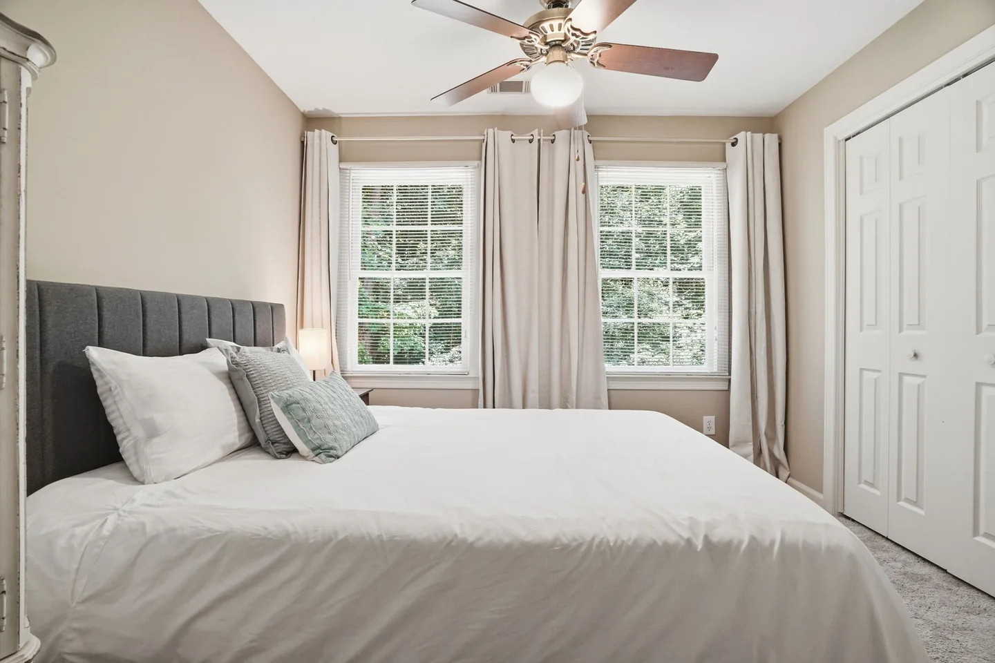Bedroom with neutral bedding and ceiling fan